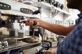 Young male barista preparing espresso at a cafe, close up