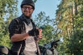 Young male biker in helmet using mobile phone and smiling sitting on a motorcycle Royalty Free Stock Photo