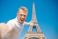 Young male blogger makes selfie photo with backpack against background of Eiffel Tower in Paris, France. Concept travel