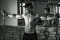 Young male bodybuilder in gym posing with metal chains