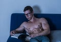 Young male bodybuilder reading book sitting on sofa Royalty Free Stock Photo