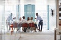 Young male boss stands leaning on table at business meeting