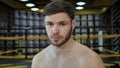 Young male boxer with a bare torso looks at the camera and strikes