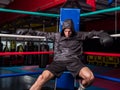 Young male boxer resting against boxe ring ropes