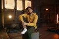 Young male breakdancer sitting on steel barrel tank