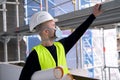 Young male builder engineer, worker or architect in white hardhat and protective respirator during inspection in construction site
