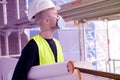 Young male builder foreman, worker or architect in white hardhat and protective respirator during inspection in construction site