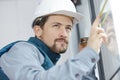 young male building contractor measuring window