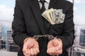 Young Male Businessman In A Classic Suit And Tie Holds His Hands In Handcuffs.