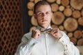 A young male businessman is getting dressed for work. A blond guy in a white shirt is trying on a bow tie. The concept