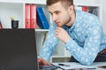 Young male businessman make notes looking at laptop sitting at office.