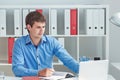 Young male businessman make notes looking at laptop sitting at office. Royalty Free Stock Photo