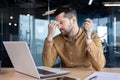 Young male businessman working overtime in the office on a laptop on a project, deadline. A tired person takes a break Royalty Free Stock Photo