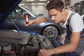 Young handsome car mechanic repairing vehicle in his garage