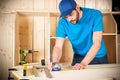 Young male carpenter with beard and metal tape measure at work. measuring wood plank woodworking construction tool concept