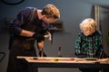 A young male carpenter is teaching woodwork to a young boy in his workshop. Royalty Free Stock Photo