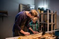 A young male carpenter is teaching woodwork to a young boy in his workshop. Royalty Free Stock Photo