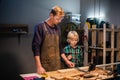A young male carpenter is teaching woodwork to a young boy in his workshop. Royalty Free Stock Photo
