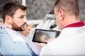 Young male Caucasian patient sitting in dental chair and consulting with his dentist Royalty Free Stock Photo