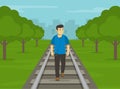 Young male character listening to loud music and walking on railway tracks during day time. Railroad safety rules and tips. Do not