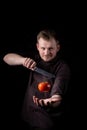 Chef with a knife tosses and catches a fresh red tomato Royalty Free Stock Photo