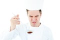 Young male chef tasting a soup with distorted face