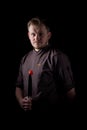 A chef in a uniform jacket shows off a professional chef`s knife and a tomato