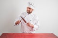 Young male chef in white uniform sharpen the knife blade