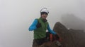 Young male climber sitting on the summit of Ruminahui volcano wearing green coat and helmet