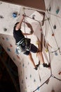 Young male climbing up on practice wall in gym Royalty Free Stock Photo