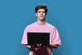 Young male college student using laptop, blue background