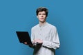 Young male college student using laptop, blue background