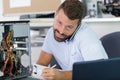 young male contractor repairing computer having phone call Royalty Free Stock Photo