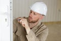 Young Male Contractor Using Screwdriver On Door Lock Mechanism