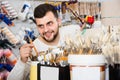 young male customer examining various types of brushes in paint store Royalty Free Stock Photo