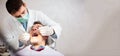 Young male dentist holding a tooth mirror and dental pick, performing dental exam on a mature male patient in dental clinic. Wide Royalty Free Stock Photo