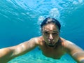 Young male diver swims in the sea in blue water and makes a selfie Royalty Free Stock Photo