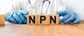 A young male doctor in blue medical gloves holds cubes with the inscription NPN. Health and medicine concept