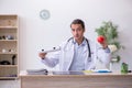 Young male doctor dietician holding apple and pizza box