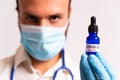Young male doctor holding covid-19 vaccine blue vial. concept of science and corona virus vaccine. face mask and stethoscope on Royalty Free Stock Photo