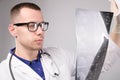 Young male doctor looking at an x-ray in a hospital on a white background, portrait of a specialist in uniform