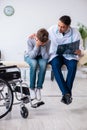 Young male doctor pediatrist and boy in wheel-chair