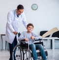 Young male doctor pediatrist and boy in wheel-chair