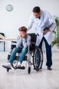 Young male doctor pediatrist and boy in wheel-chair