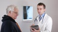 A young male doctor shows the results of tests on a tablet computer. The patient is a man aged.