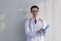 Young male doctor standing in his office holding blue gloves. Professional doctor stands up in his room office in university hospi Royalty Free Stock Photo