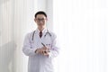 Young male doctor standing in his office holding patients file. Professional doctor stands up in his room office in university hos Royalty Free Stock Photo