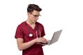 Young male doctor with stethoscope over neck working on laptop, isolated on white Royalty Free Stock Photo