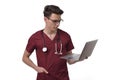 Young male doctor with stethoscope over neck working on laptop, isolated on white Royalty Free Stock Photo