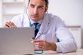 Young male doctor with stethoscope repairing computer Royalty Free Stock Photo